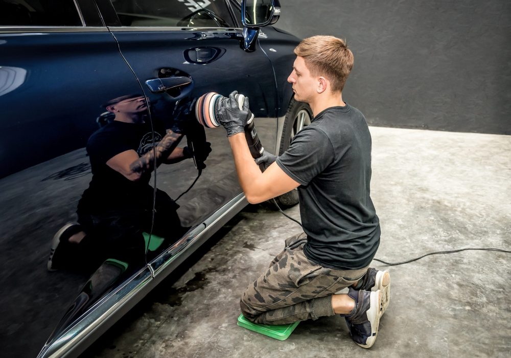 detailing specialist polishes the car body with polishing machine